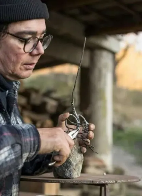 Alberto Alunni shaping a small iron sculpture on a stone